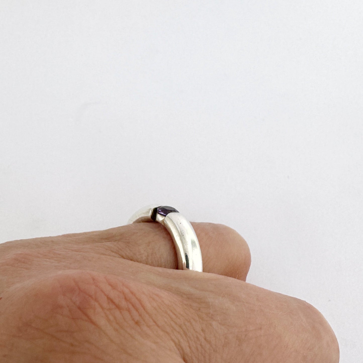 Hand showing minimalist silver ring with floating amethyst
