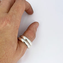 Two silver bands worn stacked on a thumb