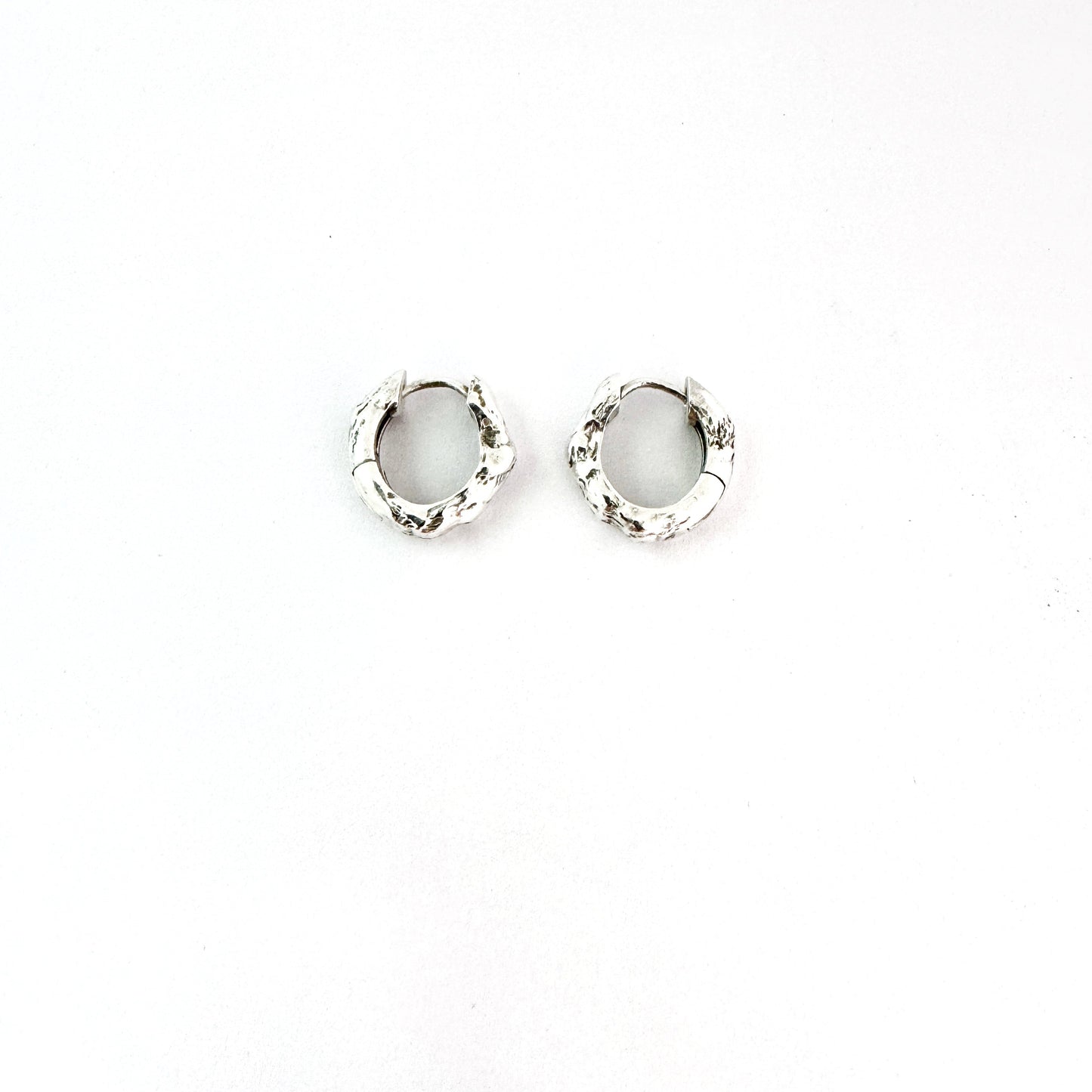 Sterling silver organic huggie earrings by Savage Jewellery on a white background