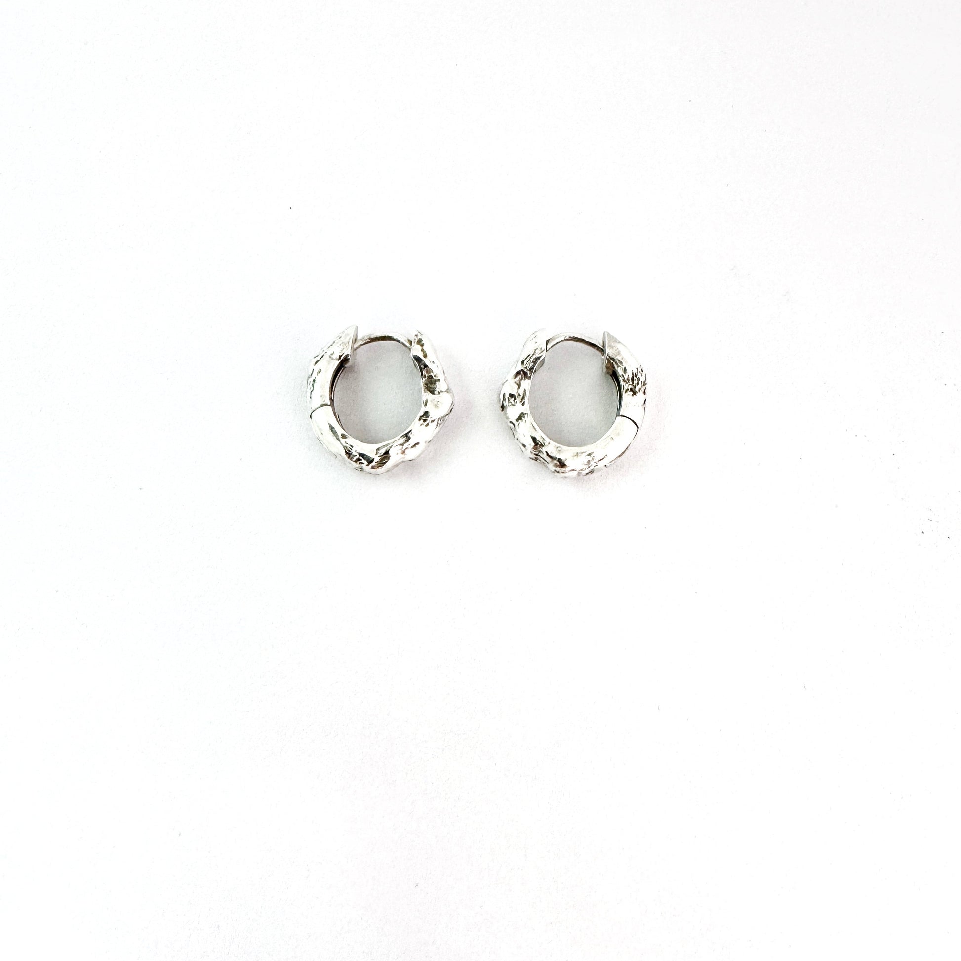 Sterling silver organic huggie earrings by Savage Jewellery on a white background