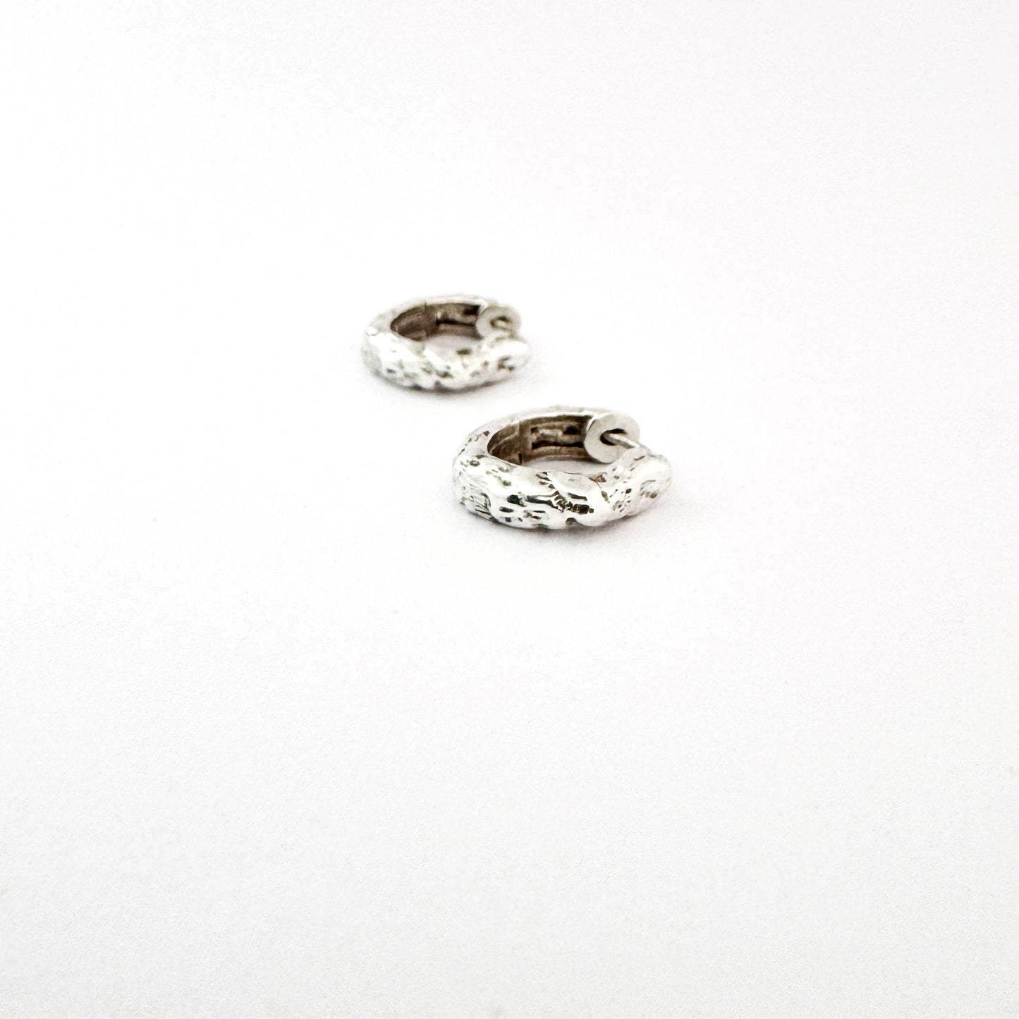 Textured sterling silver hoop style earrings on a white background