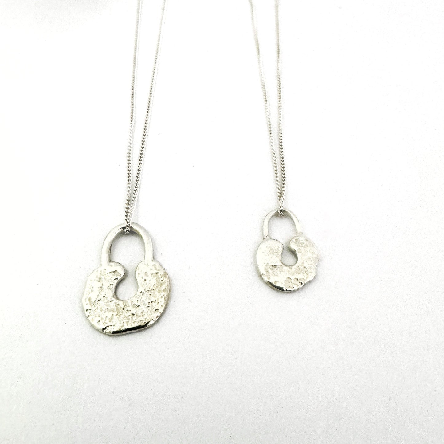 Sand cast lock pendants in size large and medium made in sterling silver by South African designer Savage Jewellery