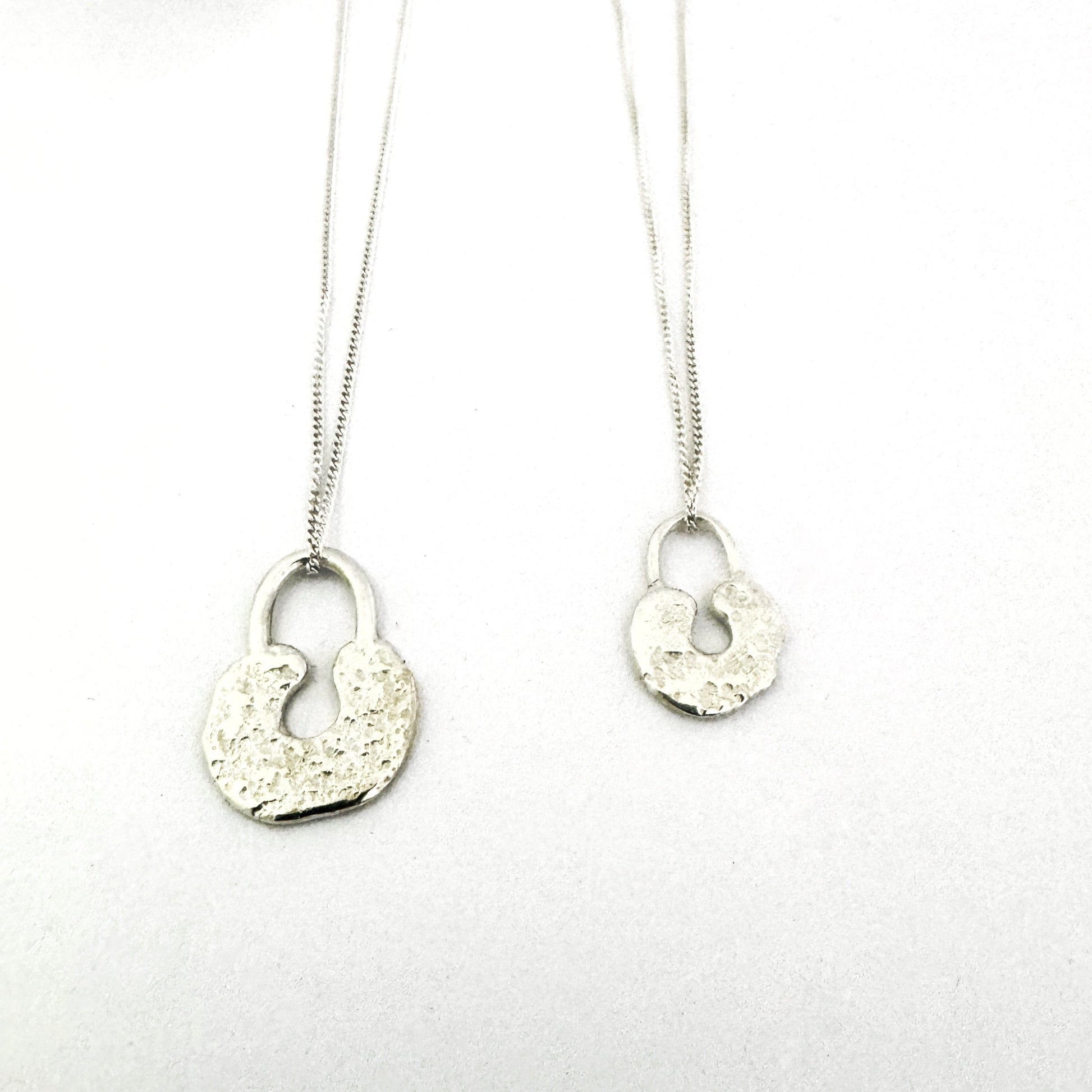 Sand cast lock pendants in size large and medium made in sterling silver by South African designer Savage Jewellery