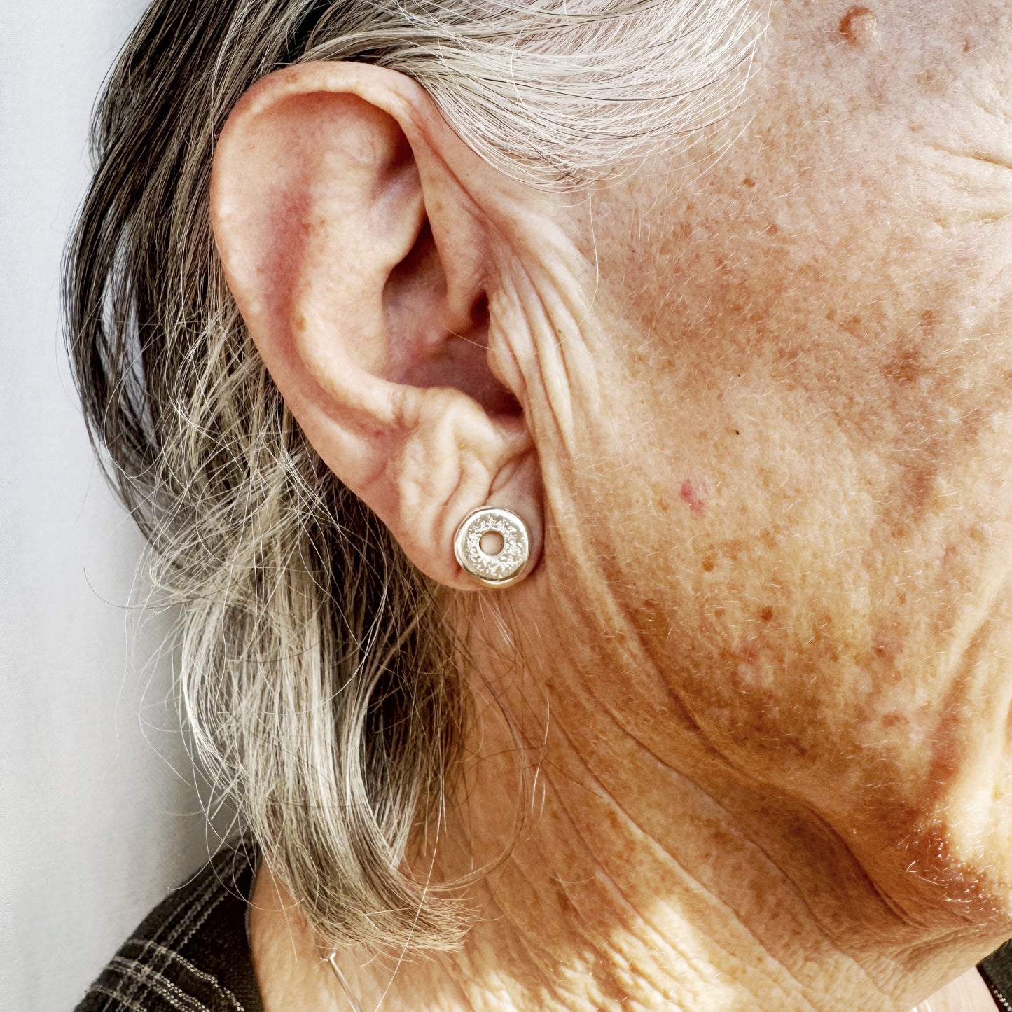 Small button earring with a sand cast texture creating a contemporary look for everyday by Savage Jewellery