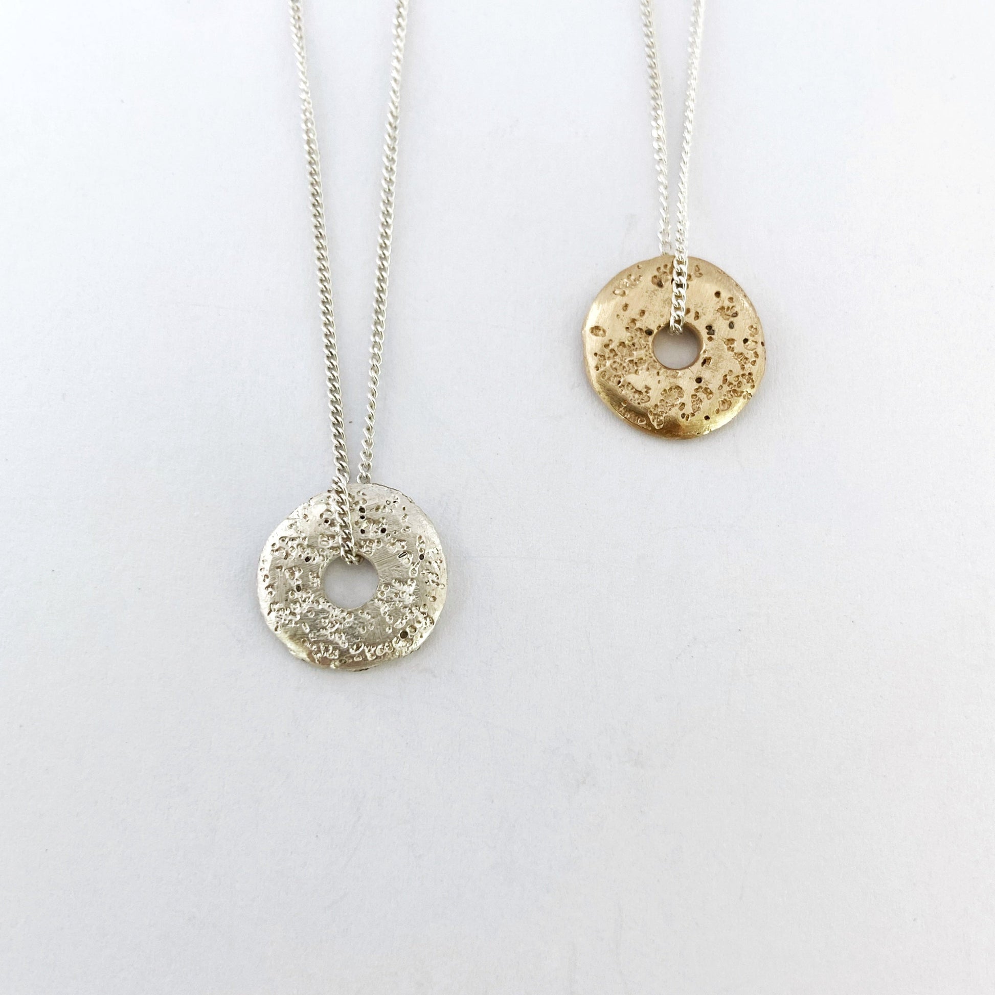 Unique sand cast donut necklaces in silver and gold by designer Savage Jewellery